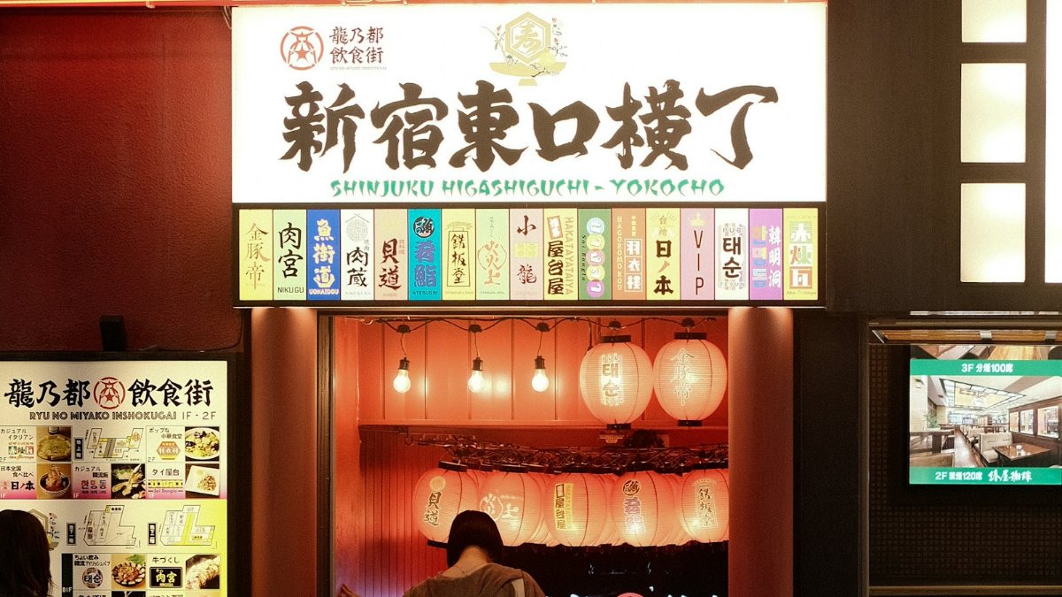 飲食店の前に立つ人と夜の路地