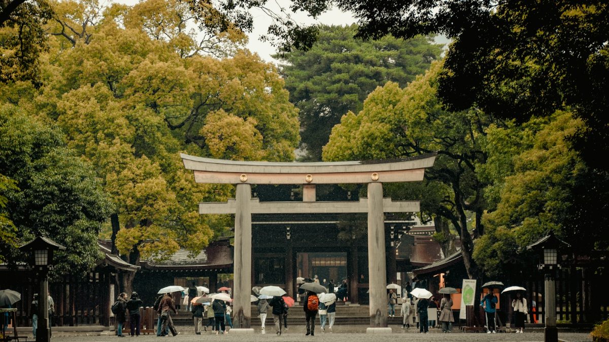 門の前に立つ傘をさした人々