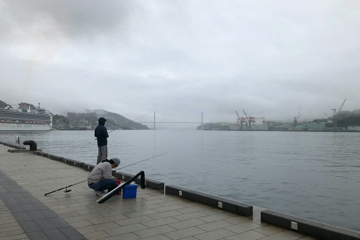 海沿いの岸壁で釣りをする人